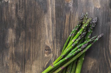 Tahta bir masada bir sürü taze kuşkonmaz. Fotoğraf seçici bir odak ile çekildi.