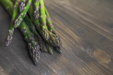 Tahta bir masada bir sürü taze kuşkonmaz. Fotoğraf seçici bir odak ile çekildi.