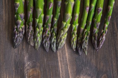 Tahta bir masada bir sürü taze kuşkonmaz. Fotoğraf seçici bir odak ile çekildi.