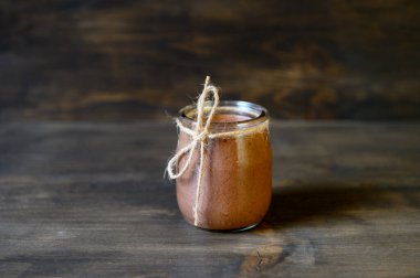 Tahta arka planda küçük bir kavanozda çikolatalı mus. Seçici odak.