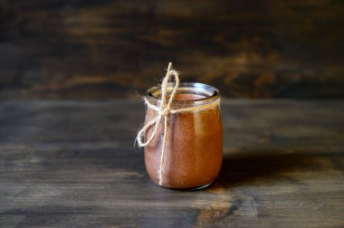 Tahta arka planda küçük bir kavanozda çikolatalı mus. Seçici odak.