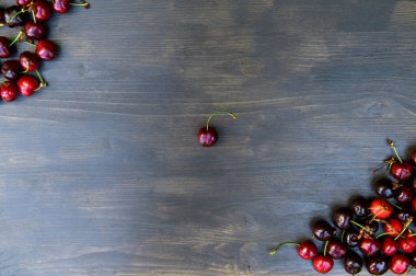 Tahta bir arka planda seramik siyah bir tabakta sulu, olgun, güzel bir kiraz..