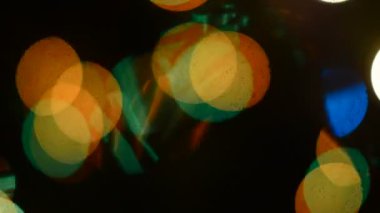 Bir ladin ağacının dallarındaki iğne siluetleri, Noel 'de sokaktaki şenlikli çelenklerin bulanık ve çok renkli ışığına karşı rüzgarda sallanıyor. Bokeh.