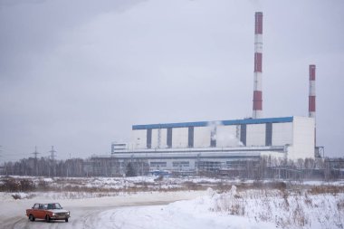 Russia, Novosibirsk - November 30, 2019. Russian car red VAZ Zhiguli is going fast in the drift, on the road against the background of the heat power station in the winter in the snow.