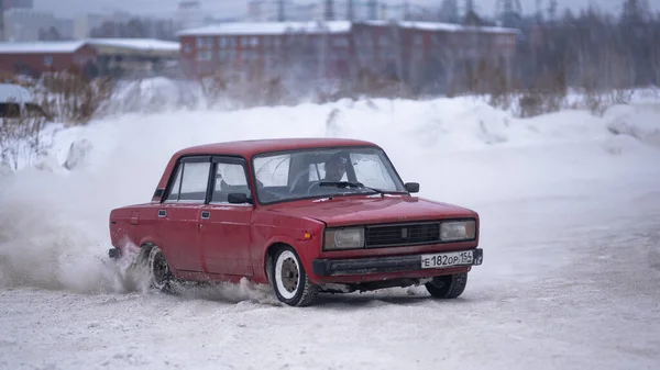 俄罗斯 Novosibirsk 2019年11月30日 在冬季 俄罗斯红色低矮的老车 Vaz Zhiguli 在冬季与一名男性司机在雪地的岔路口转弯并加雪时快速侧向行驶 — 图库照片