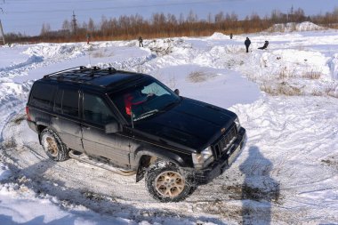 Rusya, Novosibirsk-23 Mart 2020. 4x4 Jeep Grand Cherokee off-road aracı kışın kardan geçerek tarlada keskin bir dönüş yapıyor..