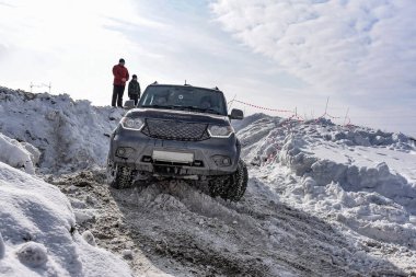 Novosibirsk, Rusya - 5 Mart 2020. Bilinmeyen insanlar, baba ve oğul, bir tepede durup Rus arazi aracına bakıyorlar. 