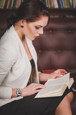 bir deri üzerinde oturan iş elbiseli çekici kadın