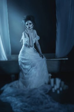 tam vücut güzel kız hayalet, cadı, vintage bakır banyo beyaz bir gölgelik, vintage yüksek vinazhnoy saç modeli ile uzun beyaz bir elbise ile oturan gelin. Studyai atış