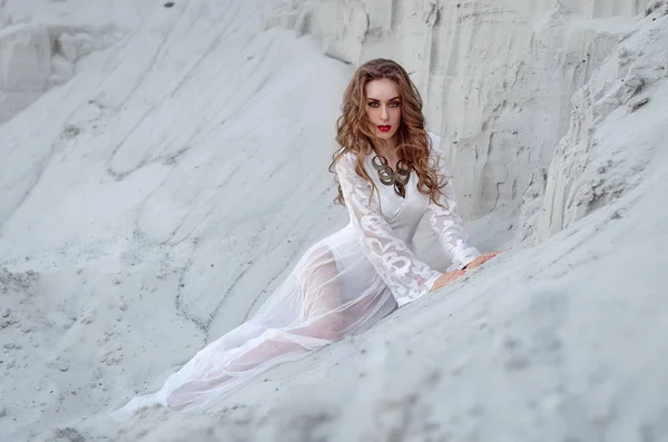 Mulher jovem na moda em um vestido longo branco está sentado no — Fotografia de Stock