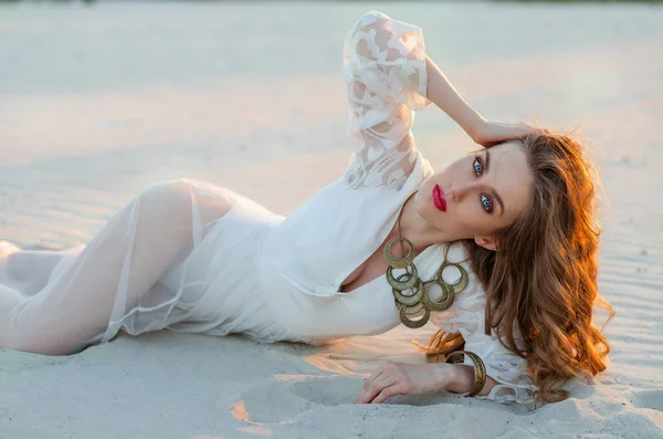 La mujer joven a la moda en un vestido largo blanco en el desierto miente —  Fotos de Stock