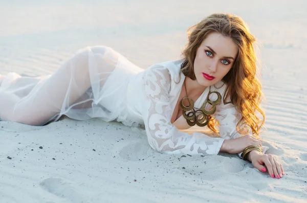 Mulher jovem na moda em um vestido longo branco no deserto mentiras — Fotografia de Stock