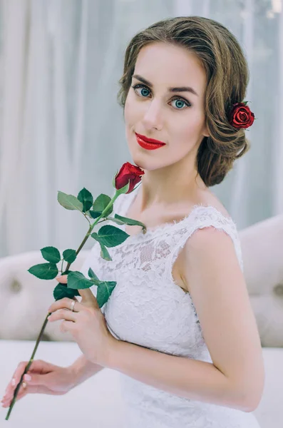 Retrato de uma jovem noiva feliz com uma rosa vermelha nas mãos — Fotografia de Stock