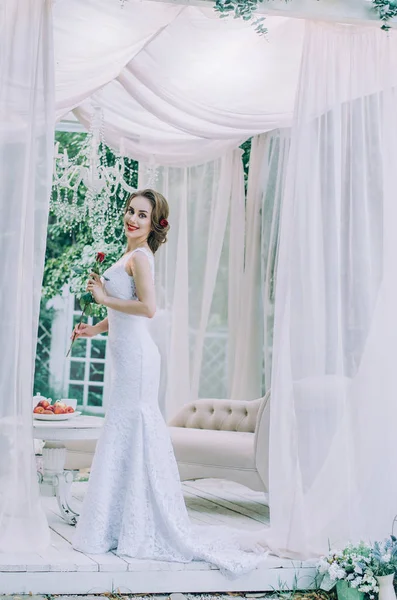 Noiva feliz em um vestido longo branco, com uma rosa vermelha em seu cabelo , — Fotografia de Stock