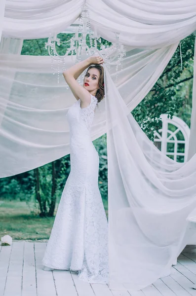 Beyaz uzun elbiseli, saçında gül kırmızı mutlu gelin,