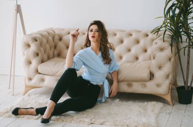 Kişilik Kuşet ve bir gömlek genç bir kadın, yüksek topuklu katta oturan kanepe yakınındaki..