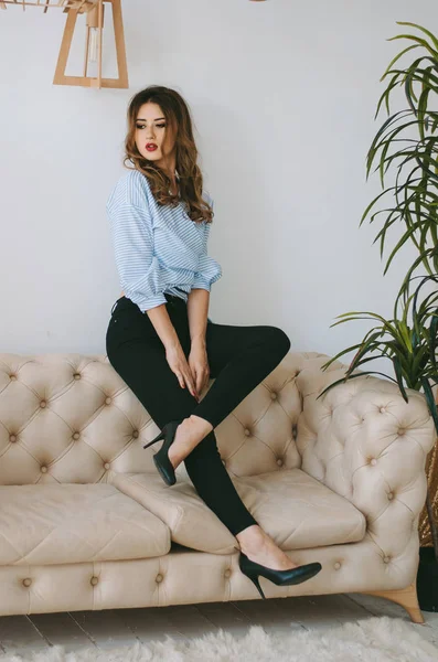 Ranza ve bir gömlek topuklu onun arkasından kanepenin arkasında oturan genç bir kadın.