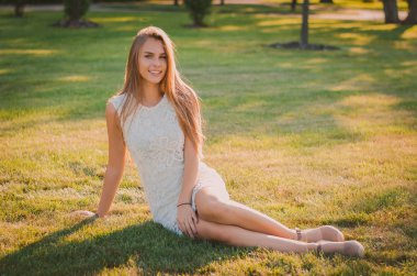 Bir yaz parkta çim üzerinde çekici genç kadın oturur