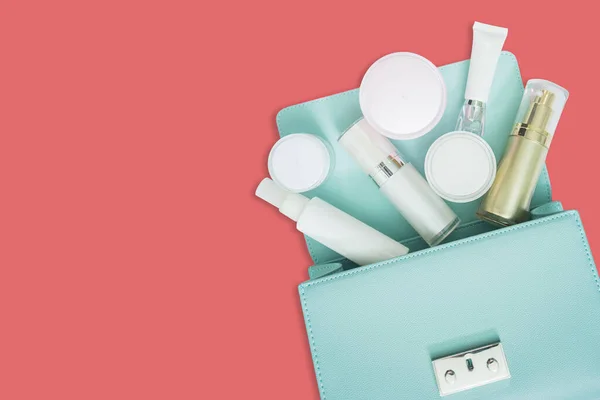 Kozmetik ürünler ve kadın çantası pembe kozmetik ürünlere izole edilmiş.