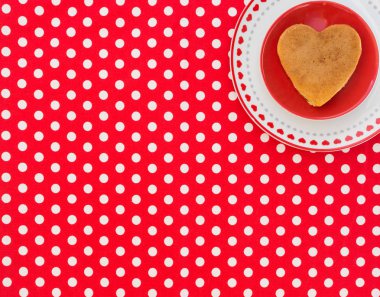 Kalp şeklinde gözleme noktalı Tekstil arka plan ile kırmızı bir plaka üzerinde