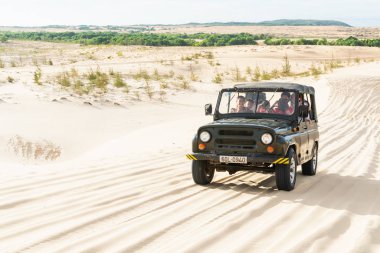 Mui Ne, Vietnam - Haziran 2019: gün doğumunda çöl kumtepelerinde giden off-road vintage sovyet arabası