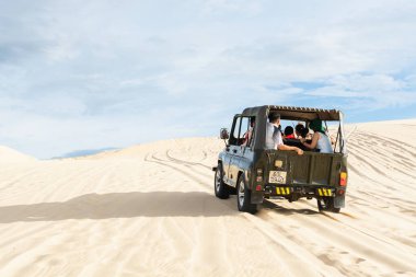 Mui Ne, Vietnam - Haziran 2019: gün doğumunda çöl kumtepelerinde giden off-road vintage sovyet arabası