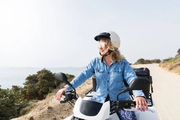 Jonge vrouw rijden quad huurfiets op zee weg in Naxos eiland, Griekenland — Stockfoto