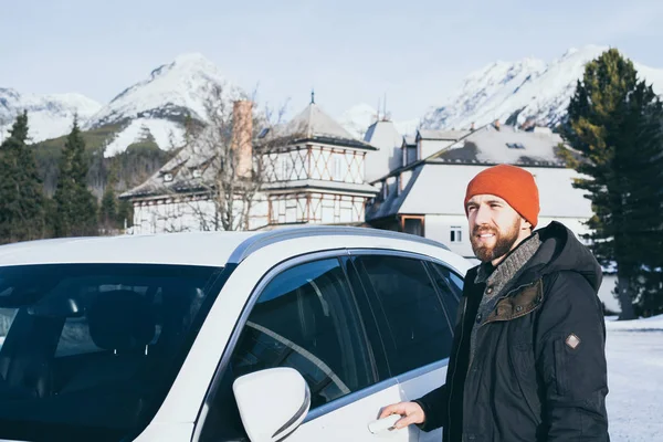 Man met baard staan naast zijn auto in Strbske Pleso met hoge Tatra bergen op de achtergrond, Slowakije — Stockfoto