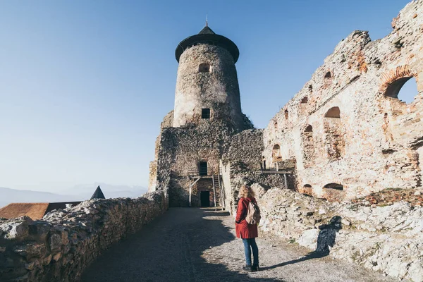 Vrouw in rode jas ontdekken Lubovniansky Hrad kasteel ruïnes in Stara Lubovna, Slowakije — Stockfoto