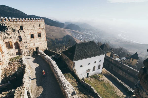 Vrouw in rode jas ontdekken Lubovniansky Hrad kasteel ruïnes in Stara Lubovna, Slowakije — Stockfoto