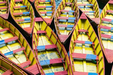 Pokhara, Nepal 'de yan yana demirlenmiş kırmızı ve sarı ahşap tekne desenleri.