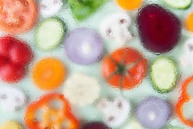 Assorted sliced vegetables on green background. Soft focus, water drops texture