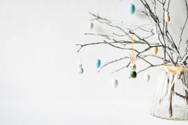 Paskalya yumurtaları, tüyler ve cam vazodaki tavşanlarla süslenmiş ağaç dallarıyla dolu sakin bir hayat.