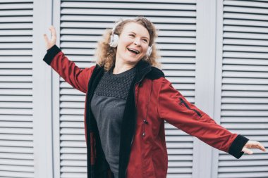 Şehir ortamında kablosuz kulaklıkla müzik dinlerken atlayan genç sarışın kadın.