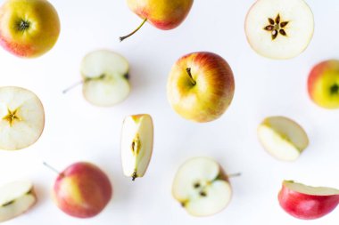 Dilimlenmiş kırmızı elmalar beyaz arka planda uçuyor.