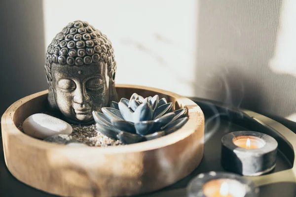 Buda heykeliyle meditasyon dekorasyonu, mum ışıkları duman ve nilüfer çiçeği..