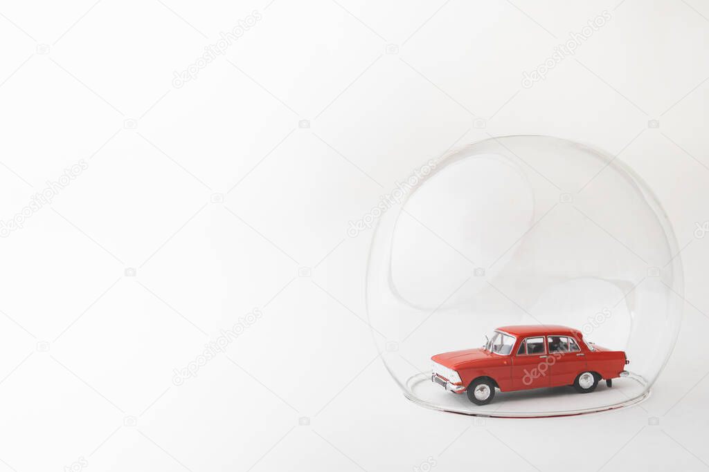 Red toy car inside a glass ball. Conceptual image of insurance coverage and safety protection.