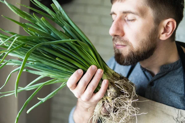 Young Man Rustic Apron Holding Smelling Bunch Green Onions Healthy — Stock Photo, Image