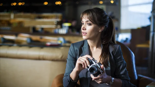 Mooi meisje fotograaf houdt camera in haar handen. Jonge vrouw zoeker te kijken en het maken van foto in café. — Stockfoto
