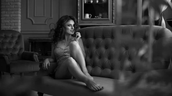 Portrait of beautiful woman in white lingerie and a black coat with curly hair posing, posing in vintage interior. Beautiful woman in erotic lingerie Stock Picture