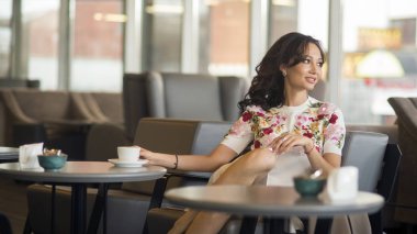 Kafede bir fincan kahve içen güzel genç bir kadın..