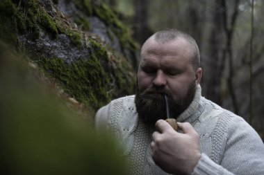 Sakallı adam ahşap pipo içiyor