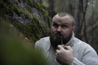 Sakallı adam ahşap pipo içiyor