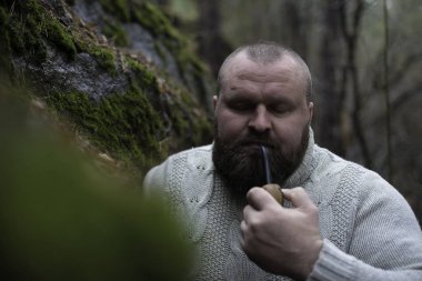 Sakallı adam ahşap pipo içiyor