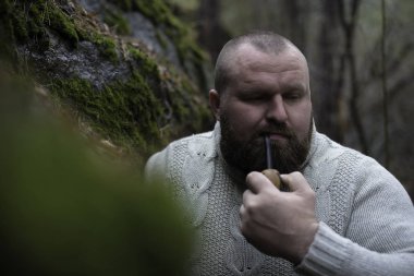 Sakallı adam ahşap pipo içiyor