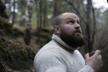 Sakallı adam ahşap pipo içiyor