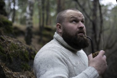 Sakallı adam ahşap pipo içiyor