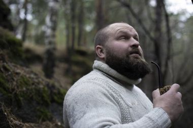 Sakallı adam ahşap pipo içiyor