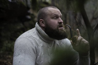 Sakallı adam ahşap pipo içiyor