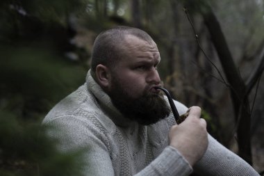 Sakallı adam ahşap pipo içiyor